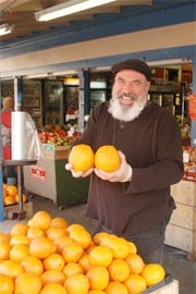 Dan Avakian shows off two large oranges at his produce market.
