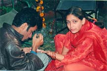 The bride's cousin has henna designs drawn on her hand during the Mendhi party.